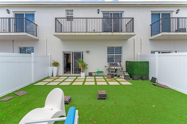 back of house with stucco siding, a yard, and a fenced backyard