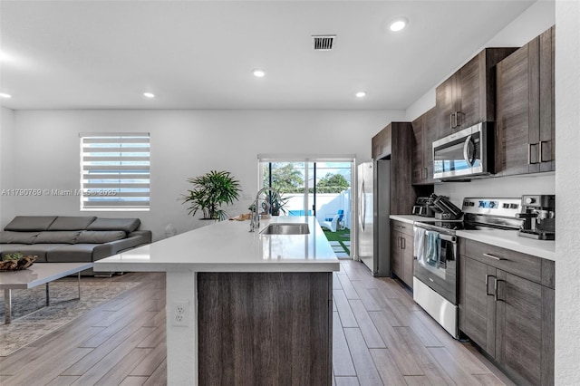 kitchen with light wood-type flooring, appliances with stainless steel finishes, light countertops, and a sink