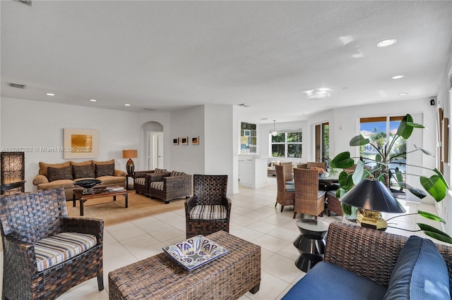 living room with light tile patterned floors, visible vents, recessed lighting, and arched walkways