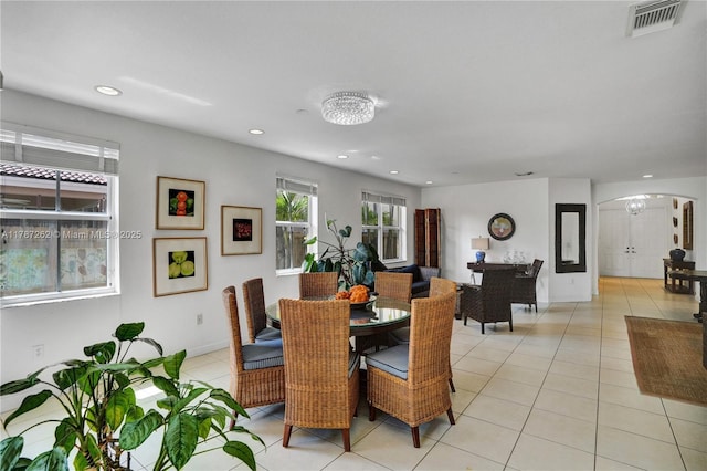 dining room with light tile patterned flooring, visible vents, baseboards, and arched walkways