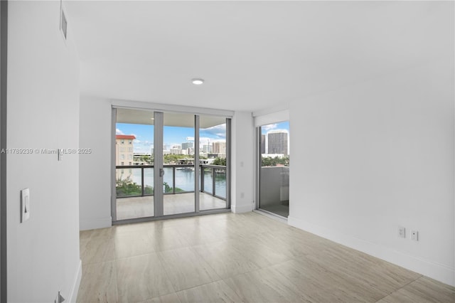 9261 E Bay Harbor Dr Unit 606, Bay Harbor Islands, FL 33154 - spare room with baseboards, visible vents, a wall of windows, and a water view