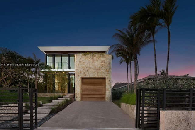 modern home featuring driveway, a garage, stucco siding, and fence