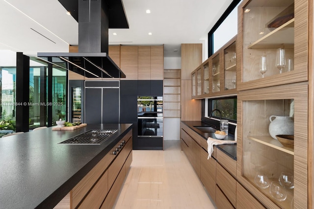 kitchen featuring a sink, modern cabinets, gas cooktop, dark countertops, and plenty of natural light