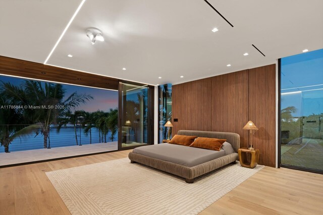 bedroom with wood finished floors, recessed lighting, access to exterior, and expansive windows