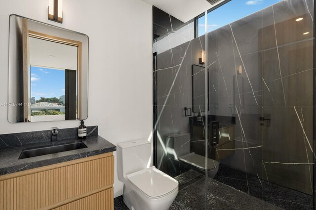 bathroom featuring toilet, a marble finish shower, and vanity