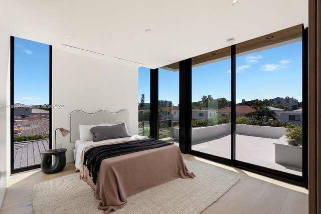 bedroom featuring floor to ceiling windows, wood finished floors, and access to exterior