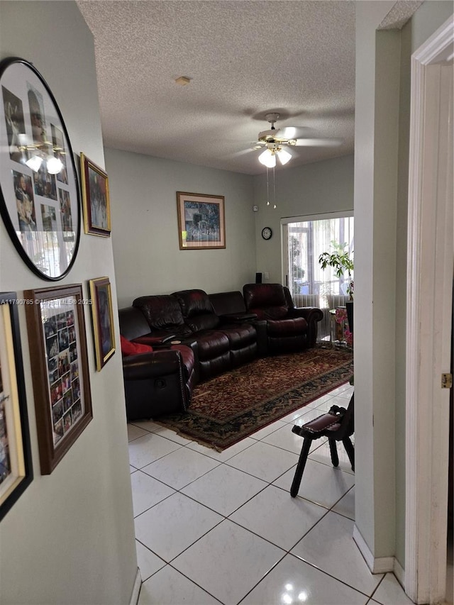 living room with light tile patterned floors, a ceiling fan, and a textured ceiling