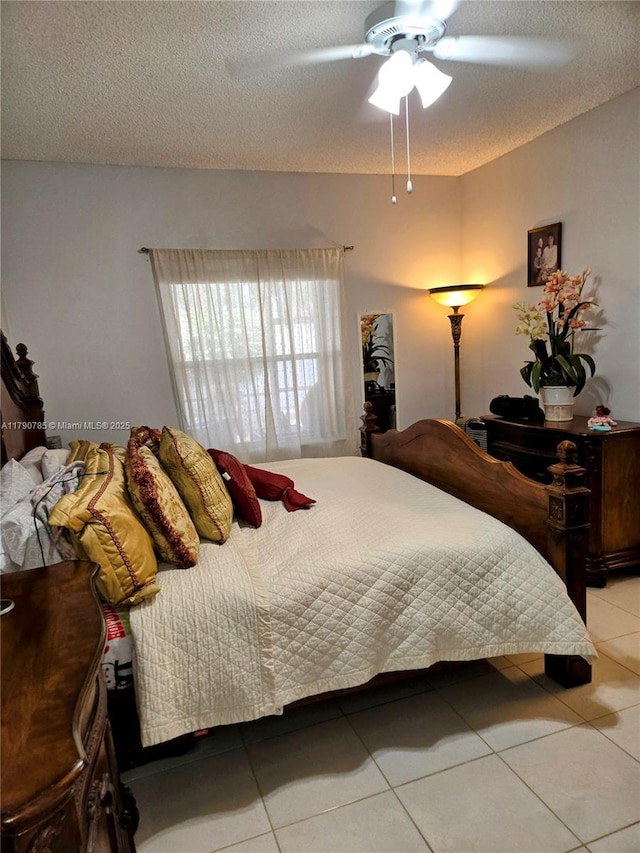 bedroom featuring light tile patterned floors, ceiling fan, and a textured ceiling