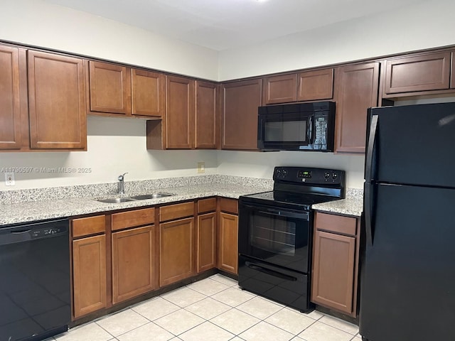 kitchen with light tile patterned floors, black appliances, light stone counters, and a sink