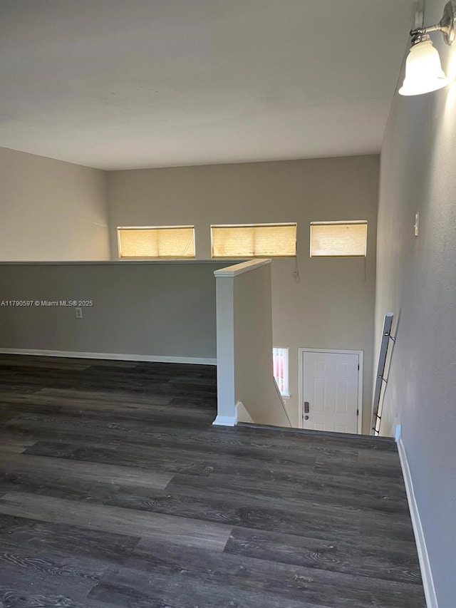 unfurnished room featuring baseboards and dark wood finished floors