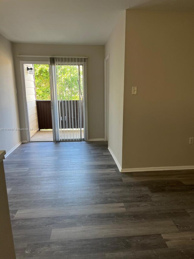 spare room featuring baseboards and dark wood finished floors