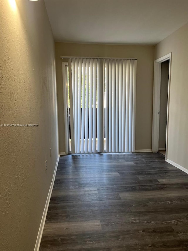 spare room featuring dark wood-type flooring and baseboards