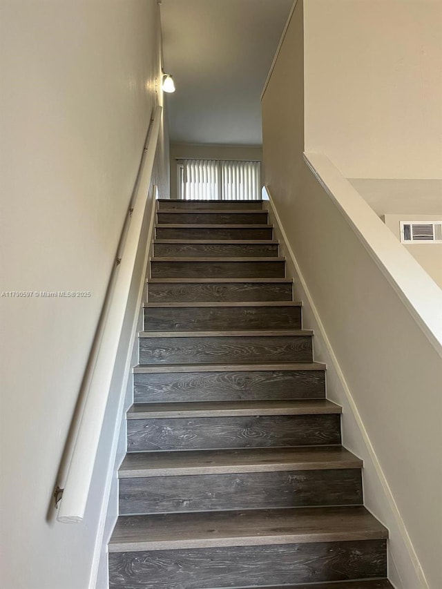 staircase with wood finished floors and visible vents