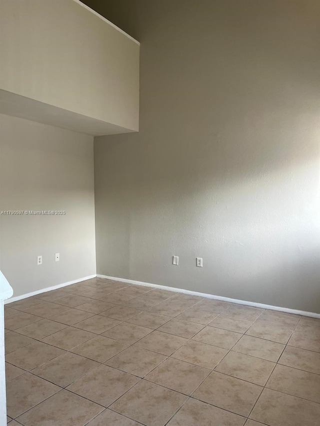 empty room featuring tile patterned floors and baseboards