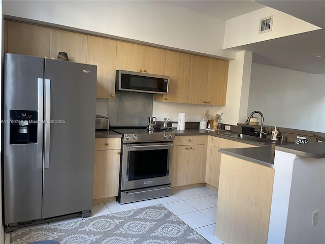kitchen with a sink, stainless steel appliances, light brown cabinetry, a peninsula, and dark countertops