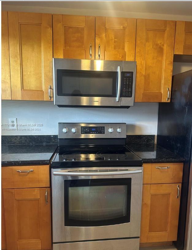 8400 Sunrise Lakes Blvd Unit 310, Sunrise, FL 33322 - kitchen featuring stainless steel appliances, dark stone countertops, and brown cabinetry