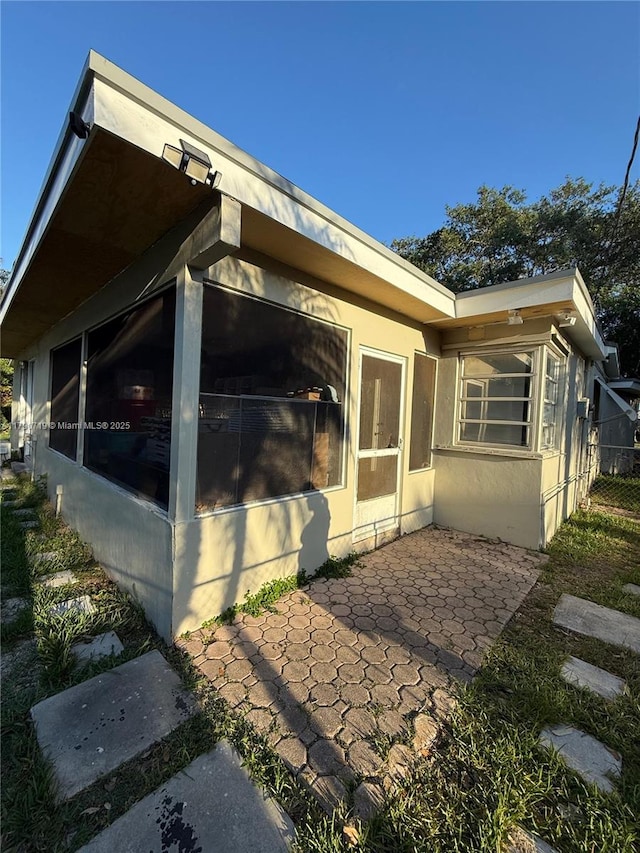 view of home's exterior featuring a sunroom, stucco siding, and a patio area