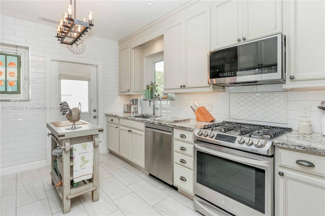 kitchen featuring a notable chandelier, a sink, appliances with stainless steel finishes, and a wealth of natural light