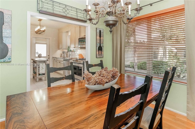 dining space featuring a notable chandelier, light wood-style floors, and baseboards