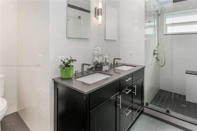 bathroom with toilet, a tile shower, tile walls, and a sink