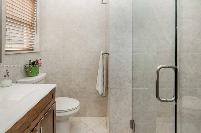 bathroom featuring tile walls, vanity, toilet, a stall shower, and tile patterned flooring