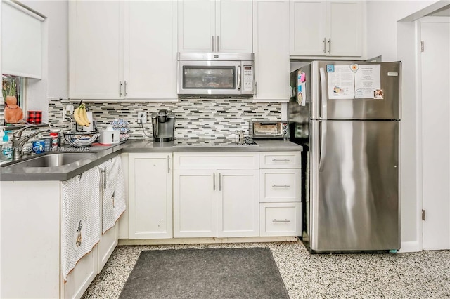 kitchen featuring stainless steel appliances, decorative backsplash, white cabinets, and a sink