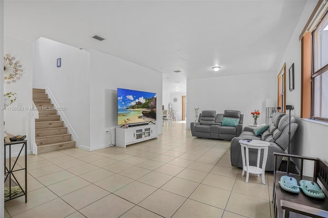 living area featuring baseboards, visible vents, light tile patterned floors, and stairway