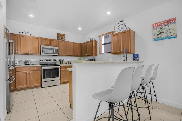 kitchen with light tile patterned floors, brown cabinets, and stainless steel appliances