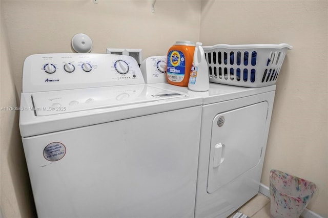 clothes washing area with tile patterned floors, washer and dryer, laundry area, and baseboards