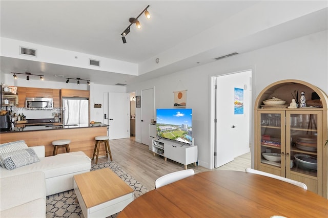 living room featuring track lighting, light wood-style floors, and visible vents