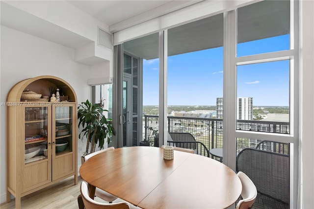 dining area with visible vents, a wall of windows, and light wood finished floors