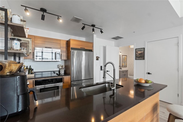 kitchen with dark countertops, a sink, appliances with stainless steel finishes, and visible vents