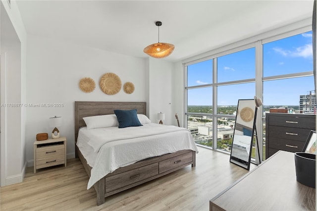 bedroom featuring baseboards, light wood-style floors, and expansive windows
