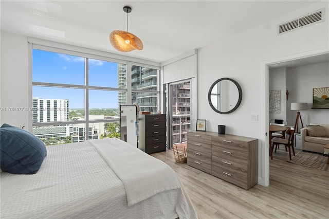 bedroom with visible vents, floor to ceiling windows, and light wood-style floors