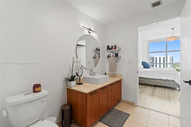 ensuite bathroom featuring vanity, ensuite bath, toilet, visible vents, and tile patterned flooring
