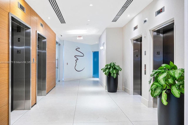 hallway featuring light tile patterned floors, elevator, and baseboards