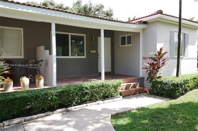 11105 NE 9th Ave, Biscayne Park, FL 33161 - view of exterior entry with stucco siding, a porch, and a tiled roof