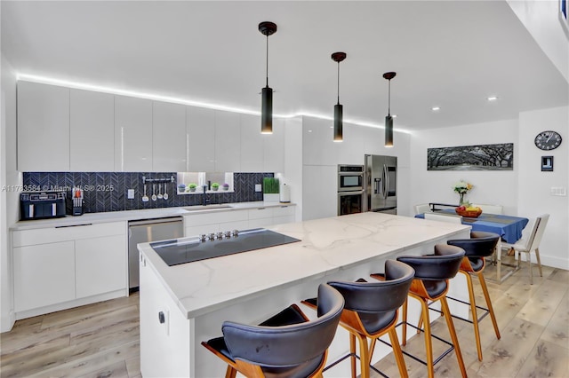 kitchen with light wood finished floors, modern cabinets, white cabinets, and stainless steel appliances