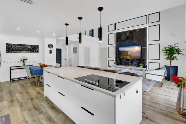 kitchen featuring modern cabinets, light wood-style floors, black electric stovetop, a kitchen island, and white cabinets
