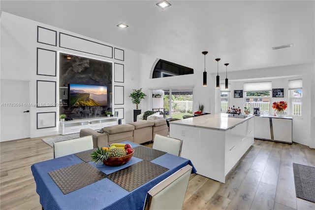 kitchen with visible vents, a center island, open floor plan, light wood finished floors, and decorative light fixtures
