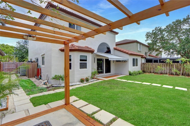 back of house featuring a pergola, a fenced backyard, a lawn, a tiled roof, and stucco siding