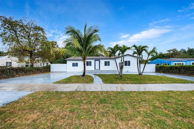 view of front facade featuring fence, a front lawn, and concrete driveway