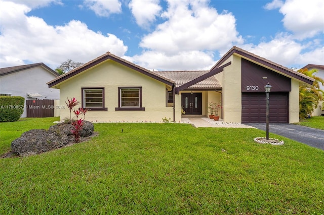 view of front of house featuring an attached garage, a front lawn, stucco siding, and a tiled roof