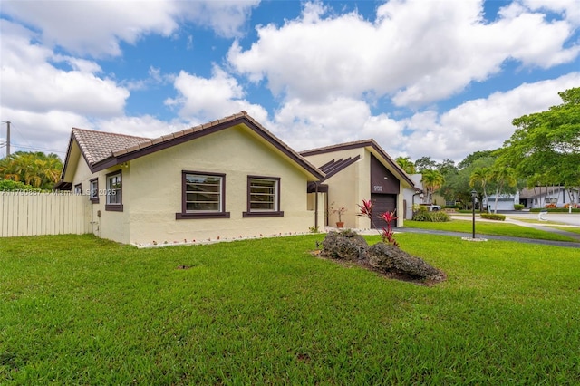 view of front of house featuring stucco siding, fence, driveway, and a front lawn