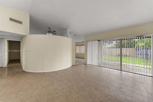 unfurnished living room featuring a wealth of natural light, visible vents, a ceiling fan, and tile patterned flooring