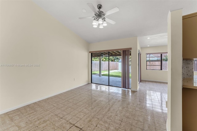 empty room featuring light tile patterned floors, a ceiling fan, vaulted ceiling, and baseboards