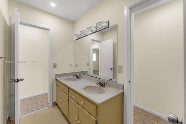 full bathroom featuring double vanity, a sink, tile patterned floors, and baseboards