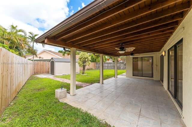 view of patio / terrace with a fenced backyard, a shed, a ceiling fan, and an outdoor structure