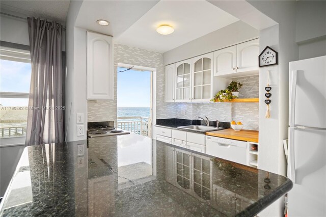 901 S Surf Rd Unit 603, Hollywood, FL 33019 - kitchen with open shelves, a sink, white appliances, white cabinetry, and tasteful backsplash