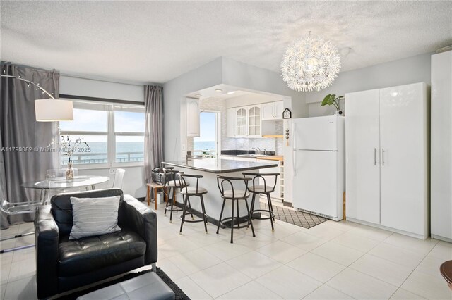 901 S Surf Rd Unit 603, Hollywood, FL 33019 - dining space with a water view, a textured ceiling, and an inviting chandelier